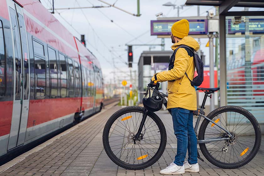 cycliste-tenant-un-velo-devant-un-train-qui-arrive-en-gare-pour-le-stationnement-velo-en-gare